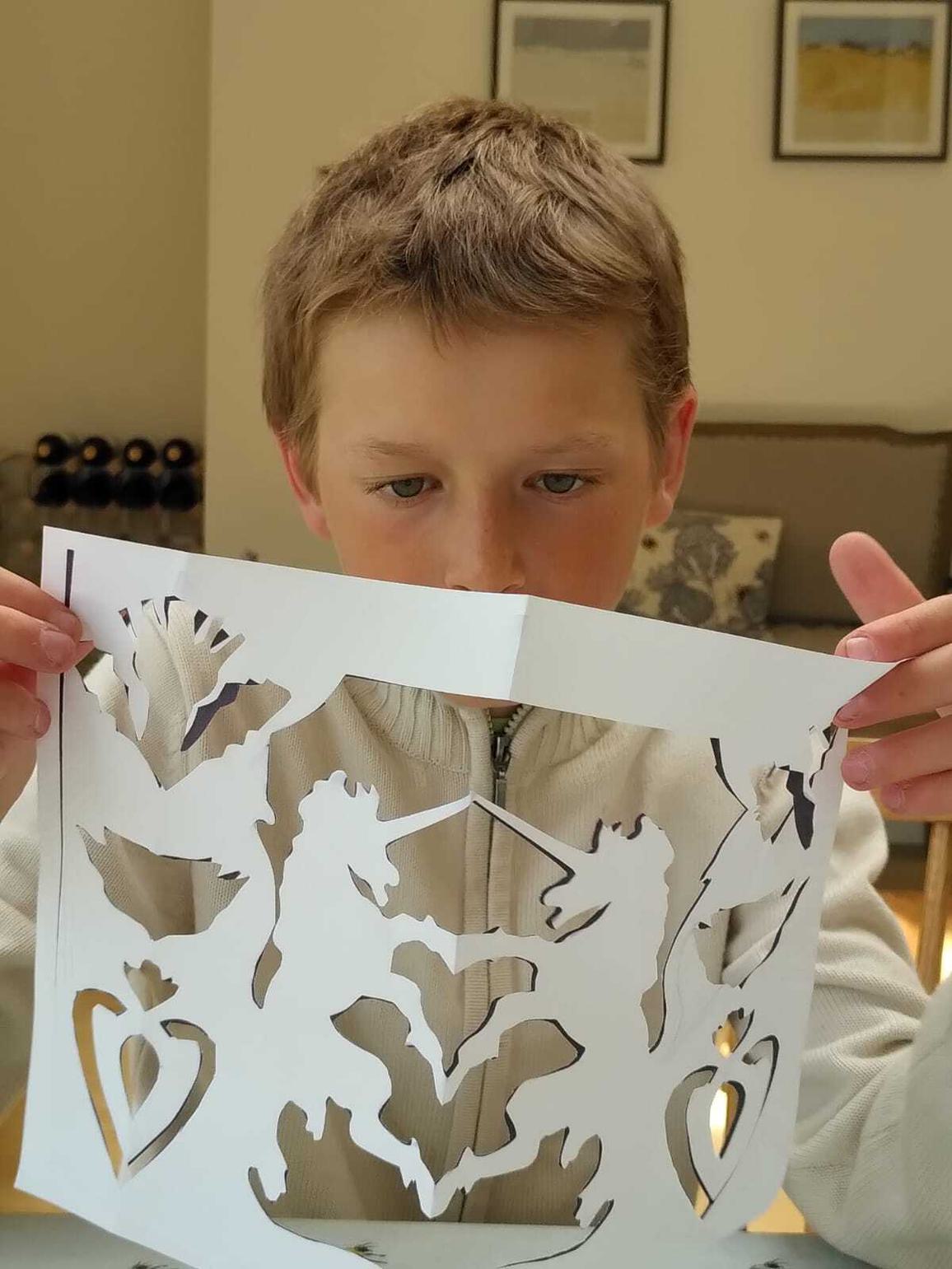 A boy holding a completed paper cut out.