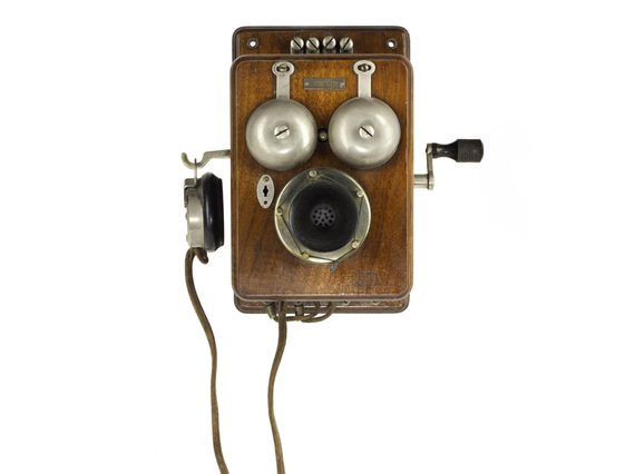Wooden wall-mounted telephone with two bells, a crank, and an earpiece hanging from the side.