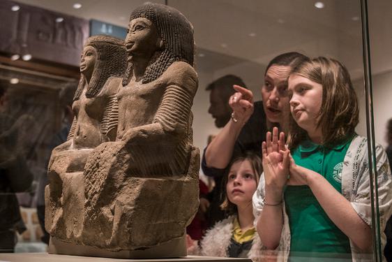 A family looking at sandstone ornaments in a case in the Ancient Egypt gallery at the Museum of Scotland