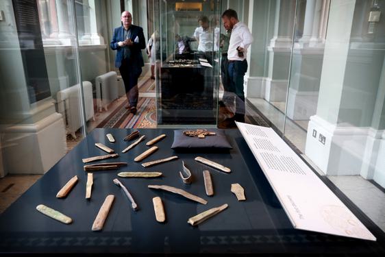 Visitors looking at objects from the Galloway Hoard in a glass museum case