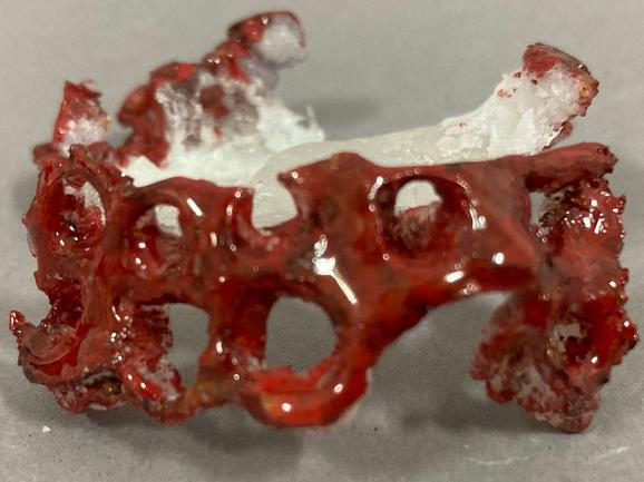 A close up of a replacement part of the glass model, painted in red